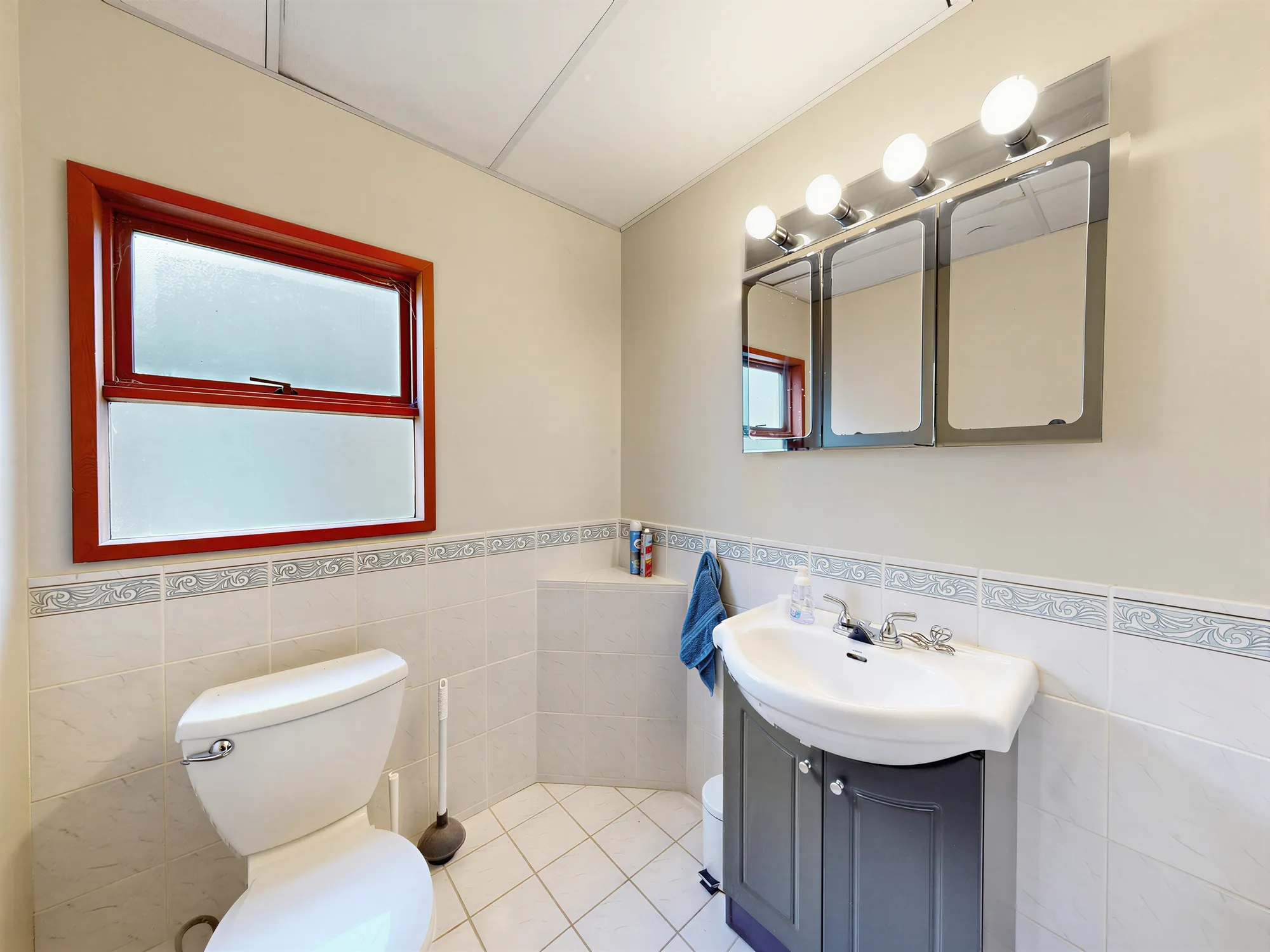 A bathroom with a tub under a window and a small vanity