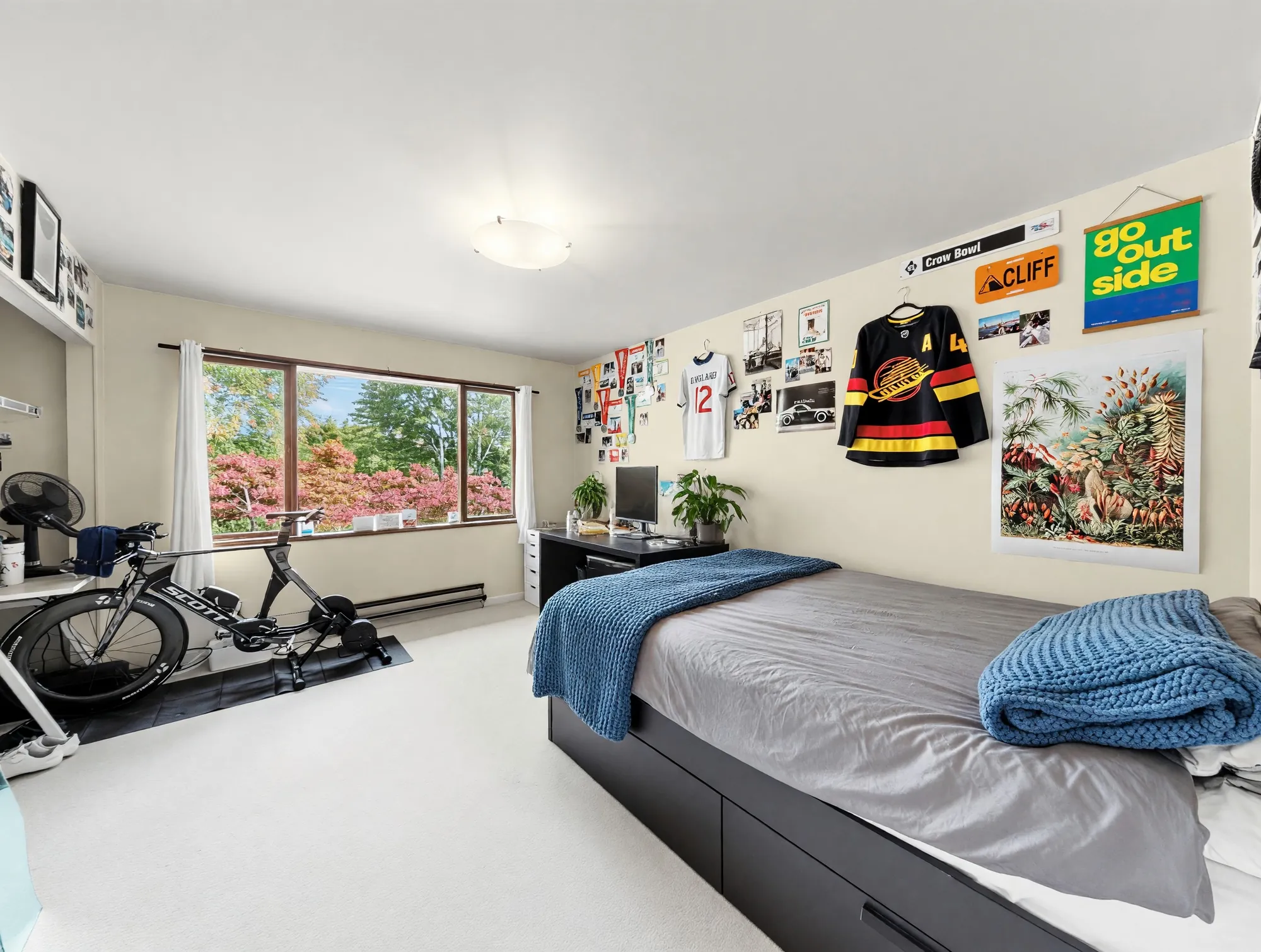A bedroom with a window running the width of the wall and a bicycle on a trainer