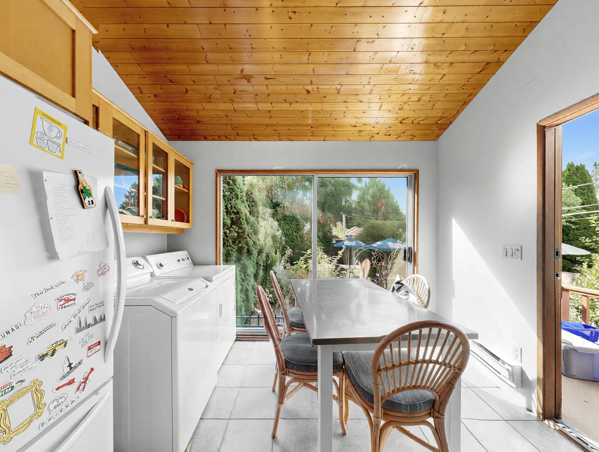 The breakfast area under a plank ceiling, with the washer and dryer against the wall
