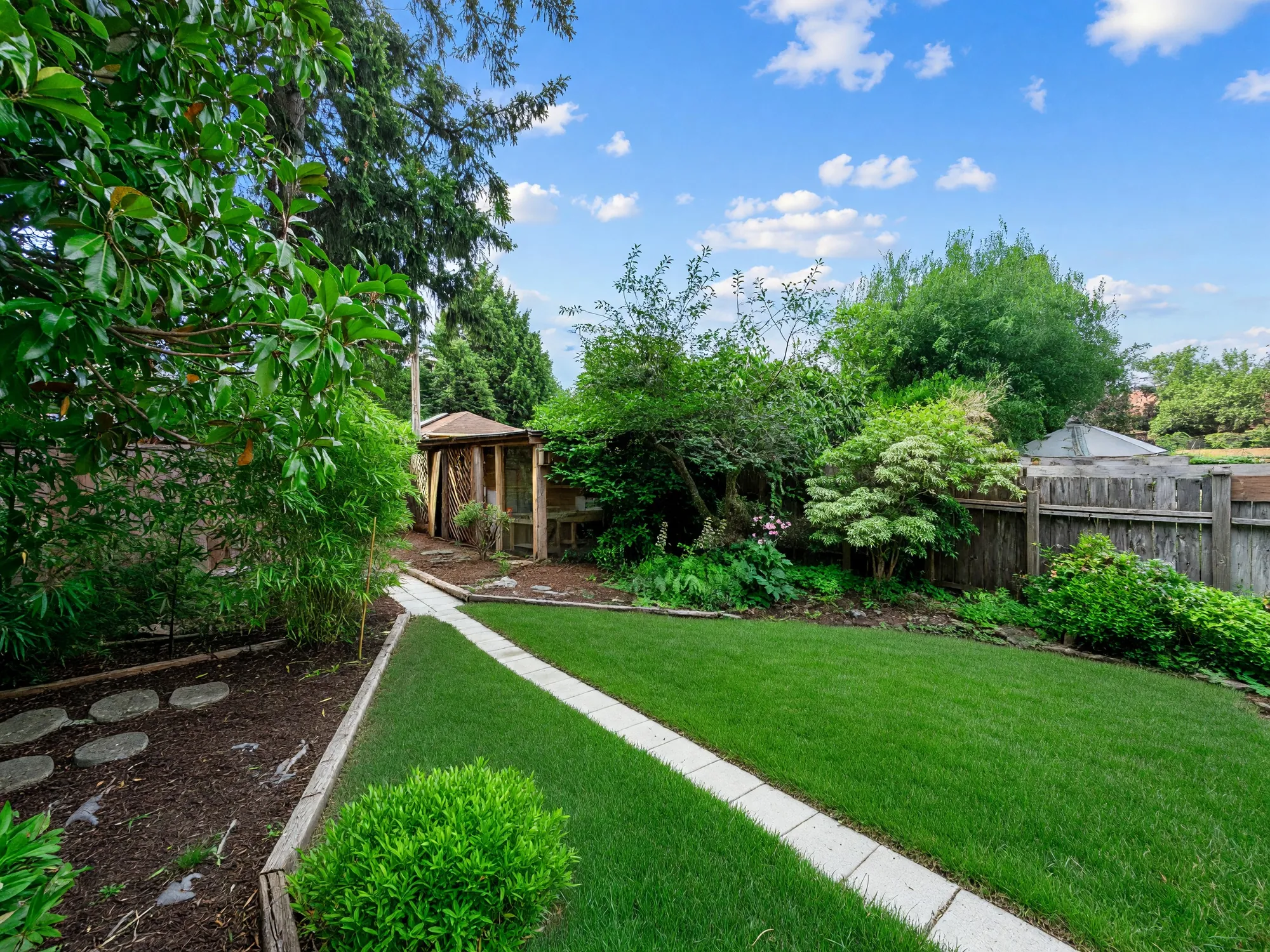 The far end of the garden with stepping stones and a small structure at the back