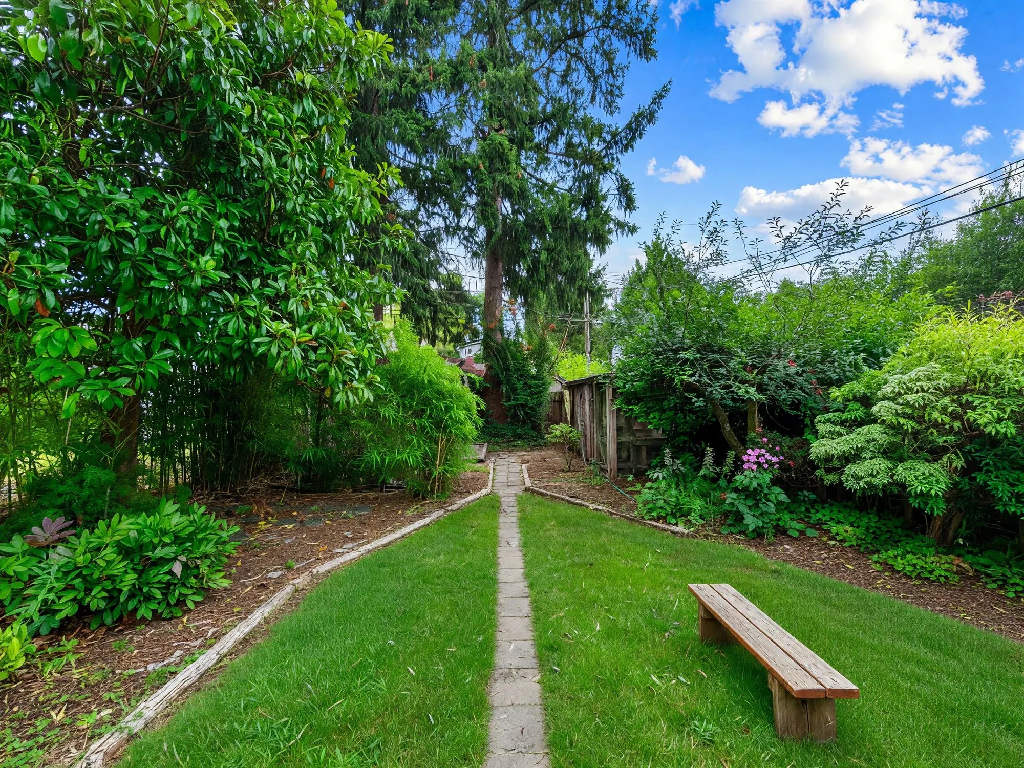 Looking down the length of the garden toward the lane, with a bench to one side