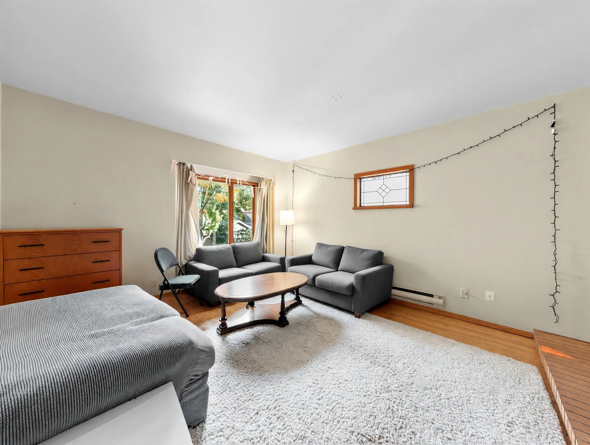 The living room from the fireplace end, carpeted, with a window to the front garden